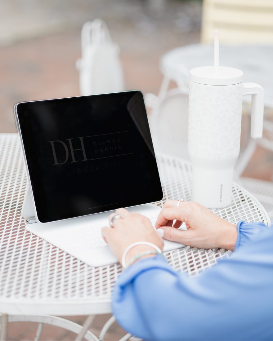 Hands typing on an iPad showing the Dianne Harris Life Coaching logo